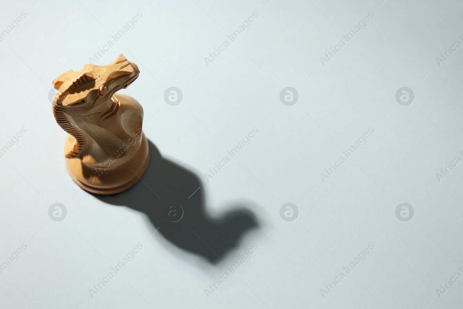 Photo of White wooden chess knight on light grey background, above view. Space for text