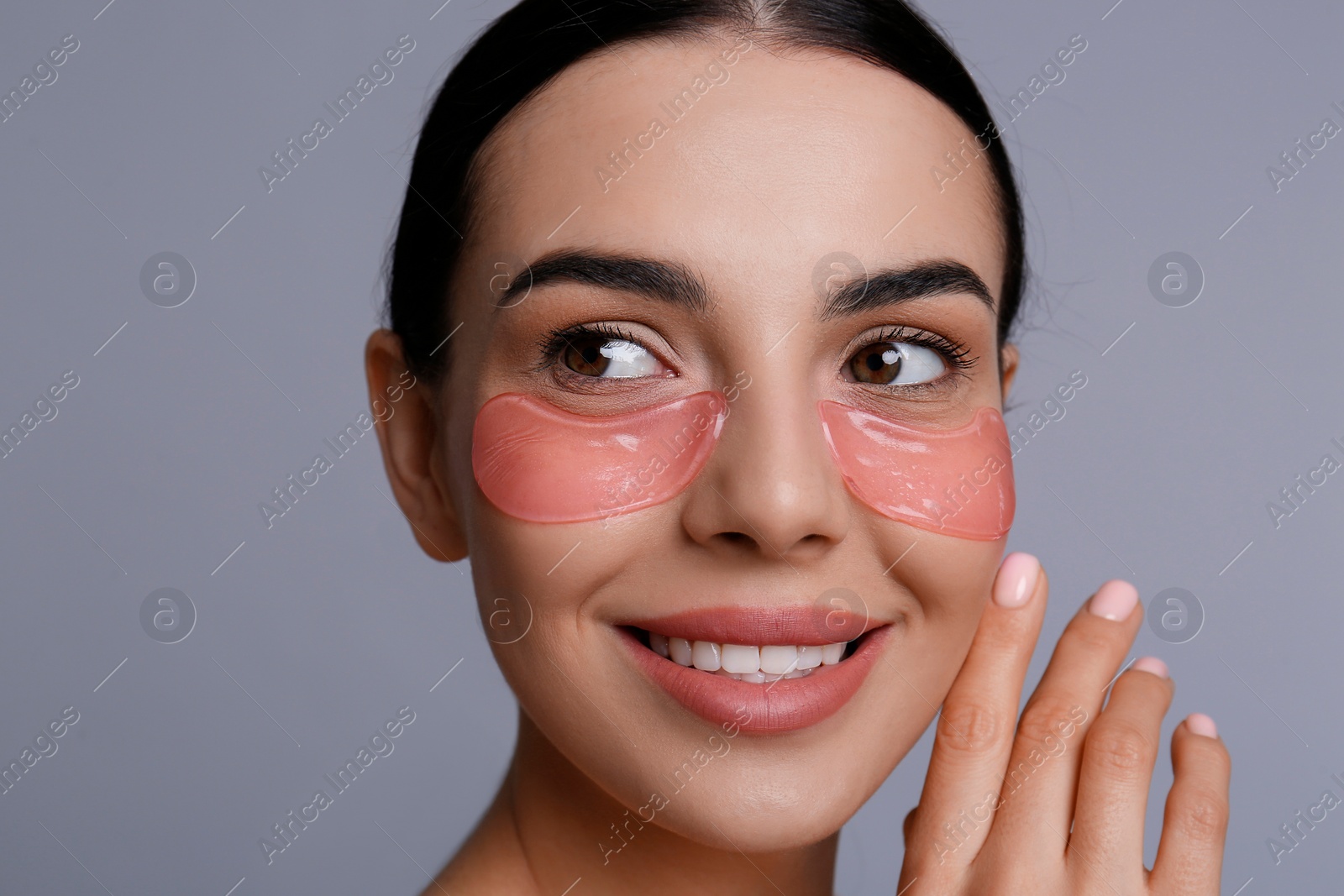 Photo of Beautiful young woman with under eye patches on grey background