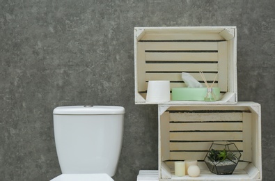 Photo of Toilet bowl and decor elements near grey wall. Bathroom interior