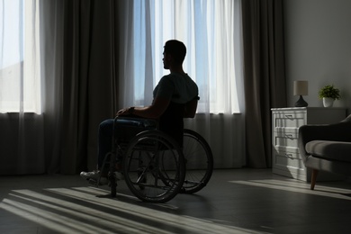 Photo of Young man sitting in wheelchair near window indoors