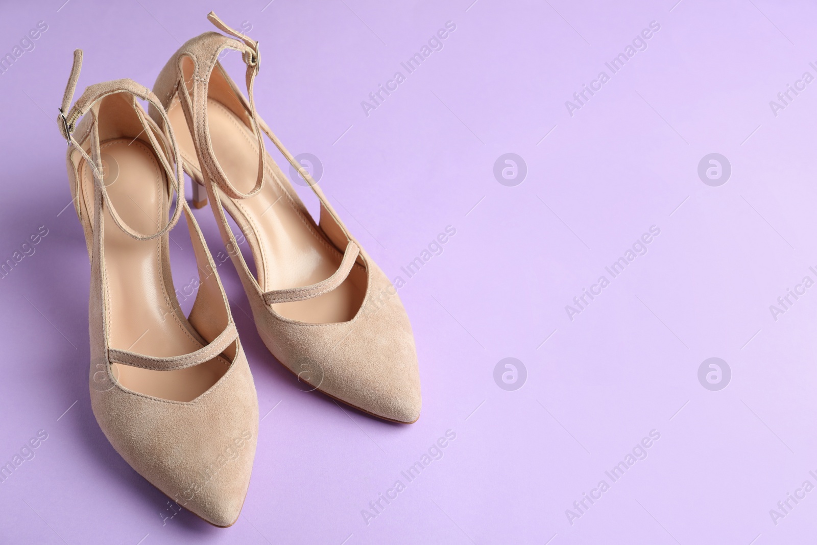 Photo of Stylish high heeled shoes on violet background. Space for text