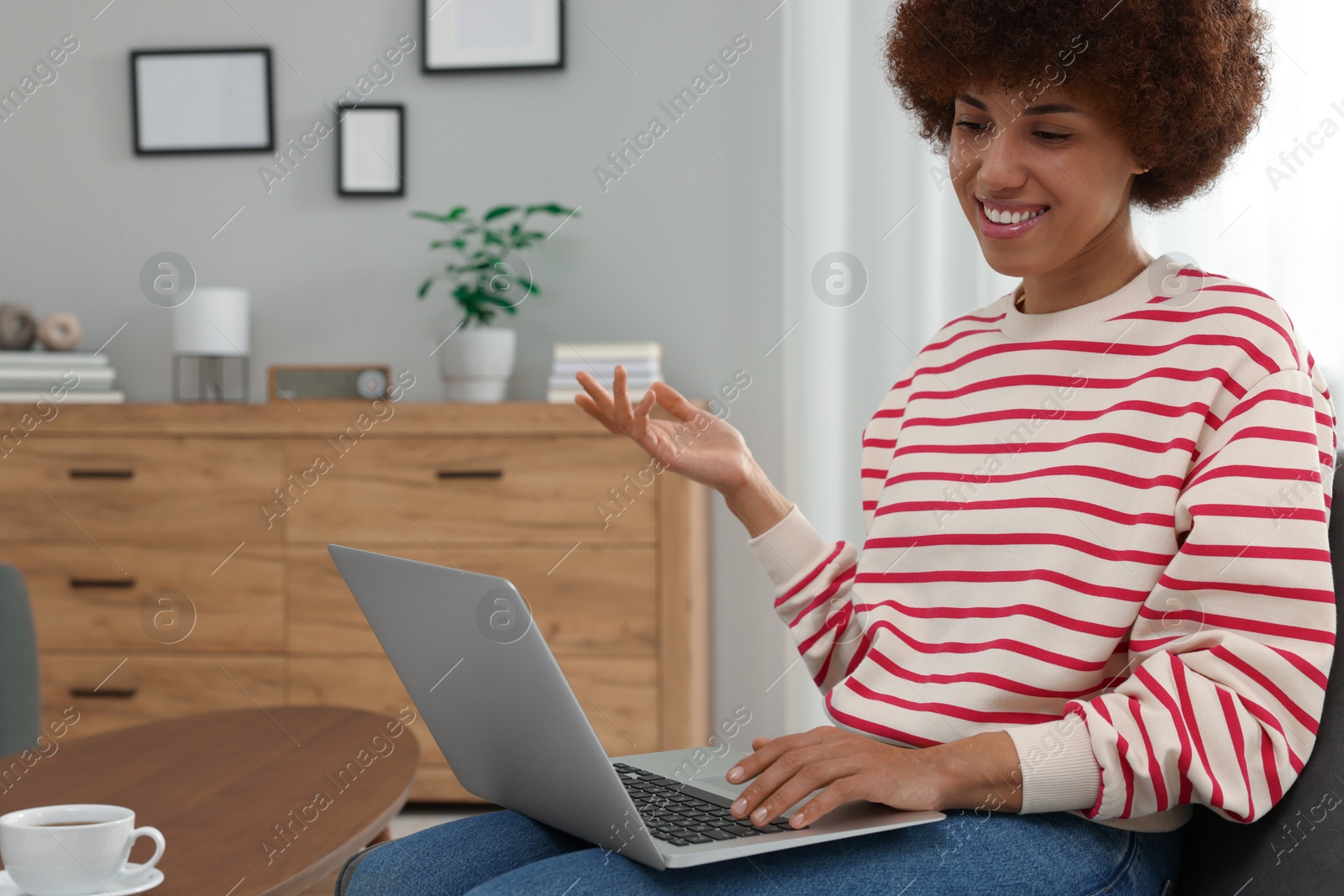 Photo of Beautiful young woman having video chat via laptop in room