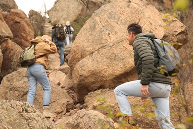 Group of hikers with backpacks climbing up mountains