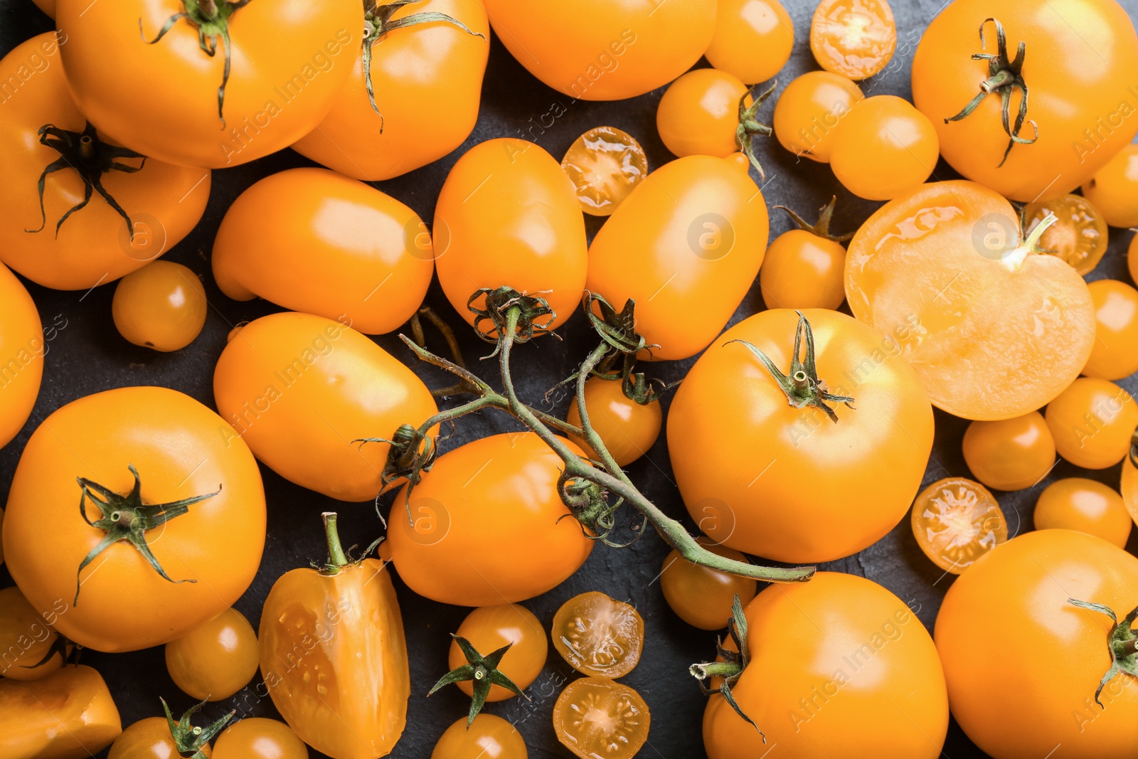 Photo of Ripe yellow tomatoes on black table, flat lay