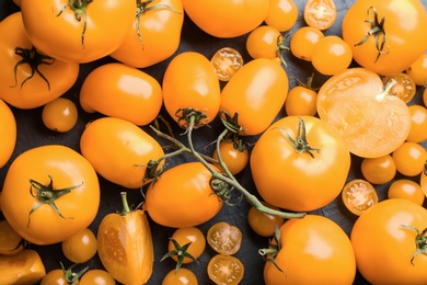 Photo of Ripe yellow tomatoes on black table, flat lay