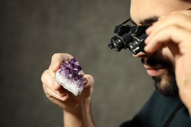 Photo of Male jeweler evaluating semi precious gemstone in workshop, closeup