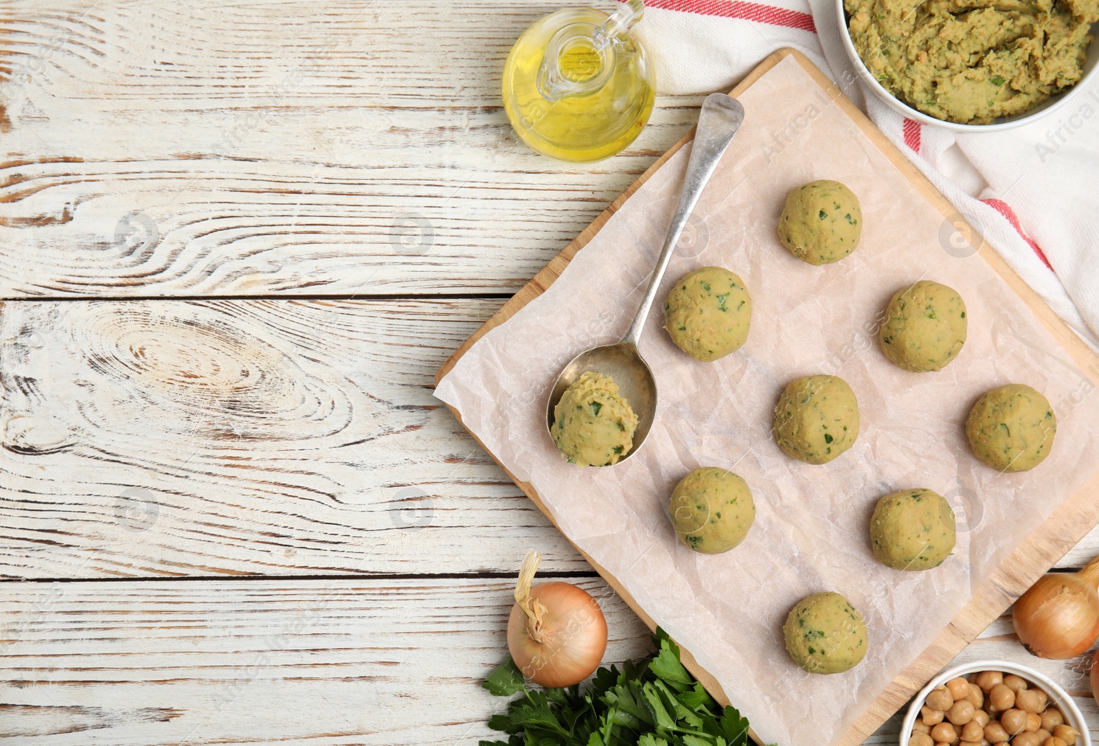 Photo of Raw falafel balls and ingredients on white wooden table, flat lay. Space for text