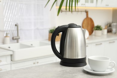 Photo of Electric kettle and cup on table in kitchen. Space for text