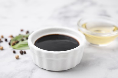 Photo of Bowl with balsamic vinegar on white table, closeup