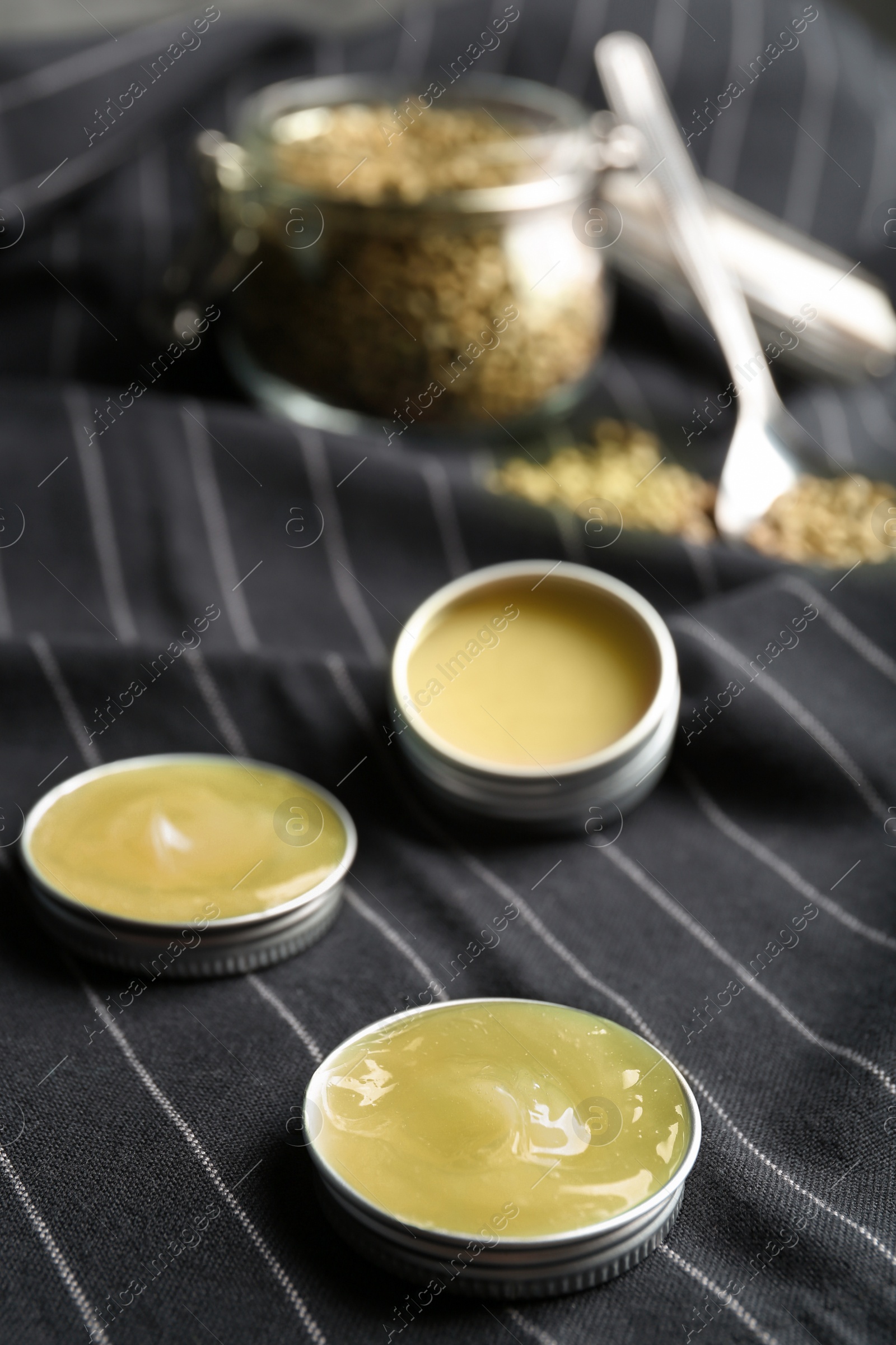 Photo of Containers with hemp lotion on striped fabric