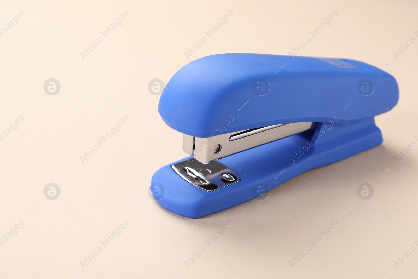 Photo of Blue stapler on beige background. Space for text
