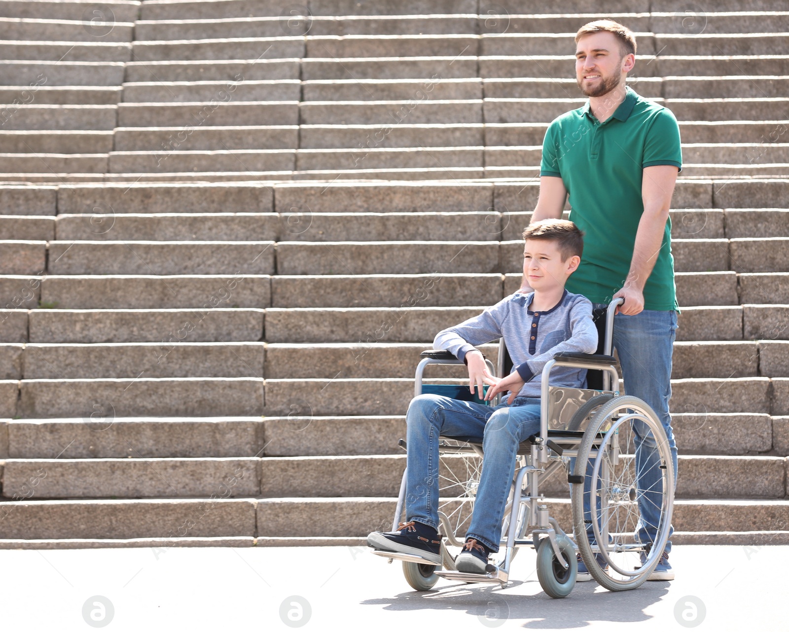 Photo of Preteen boy in wheelchair with his father outdoors