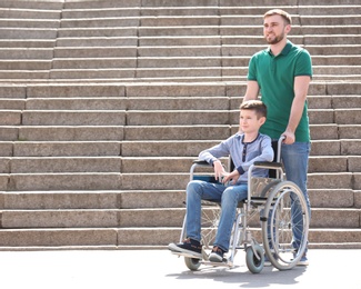 Preteen boy in wheelchair with his father outdoors