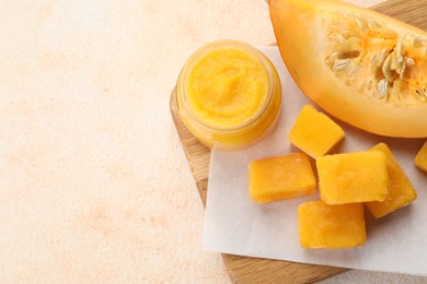 Photo of Frozen pumpkin puree cubes with ingredient on beige table, top view. Space for text