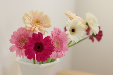 Photo of Vase with beautiful gerbera flowers on blurred background, closeup