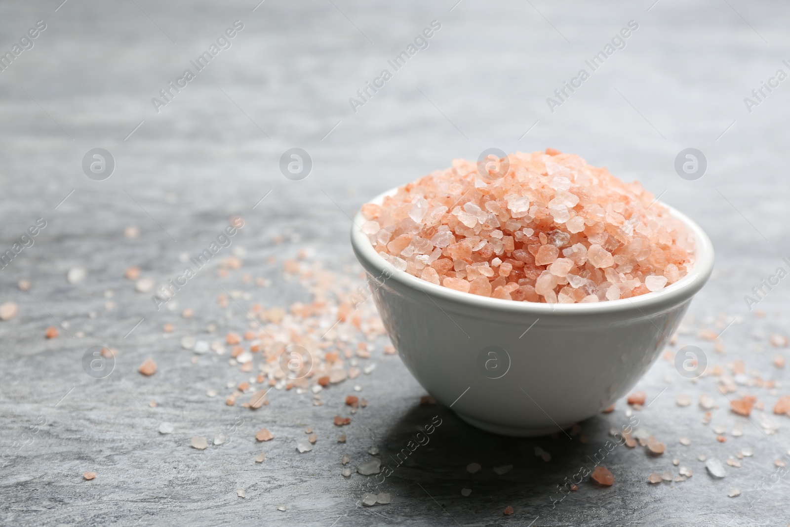 Photo of Pink himalayan salt on grey table, closeup. Space for text