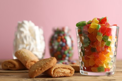 Delicious candies in glass and cookies on wooden table, closeup