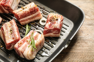 Photo of Grill pan with raw ribs and seasonings on wooden table, closeup