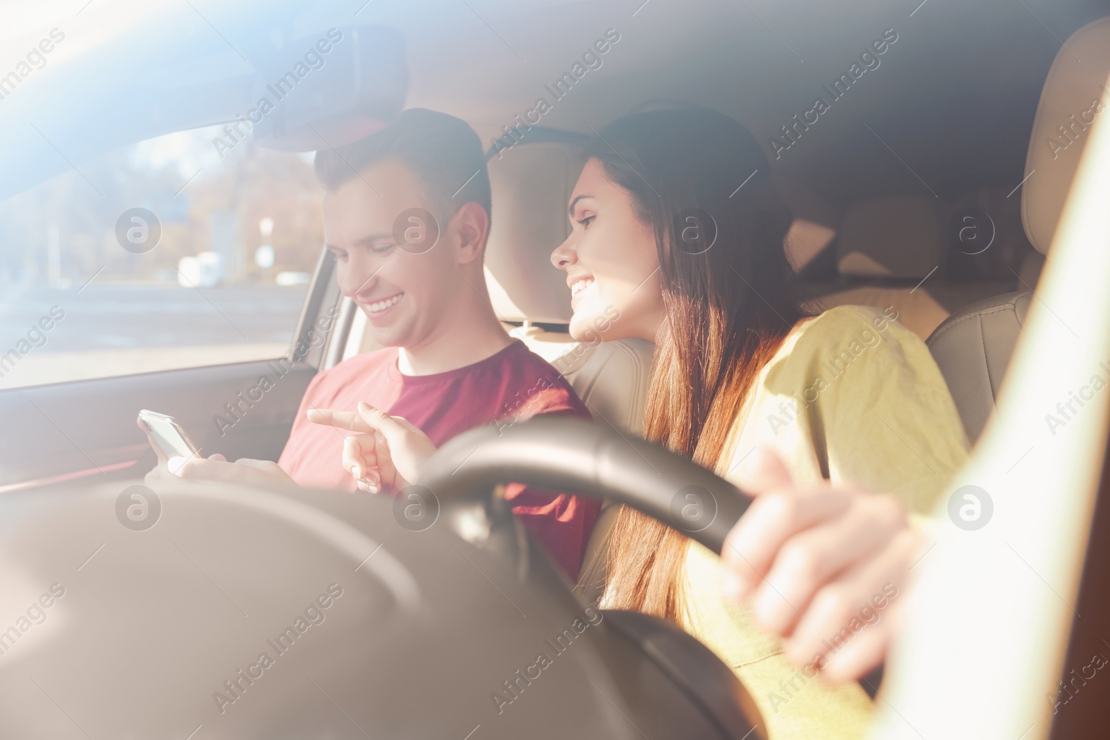 Photo of Happy young couple looking at smartphone in car