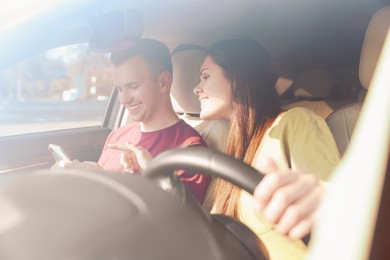 Happy young couple looking at smartphone in car