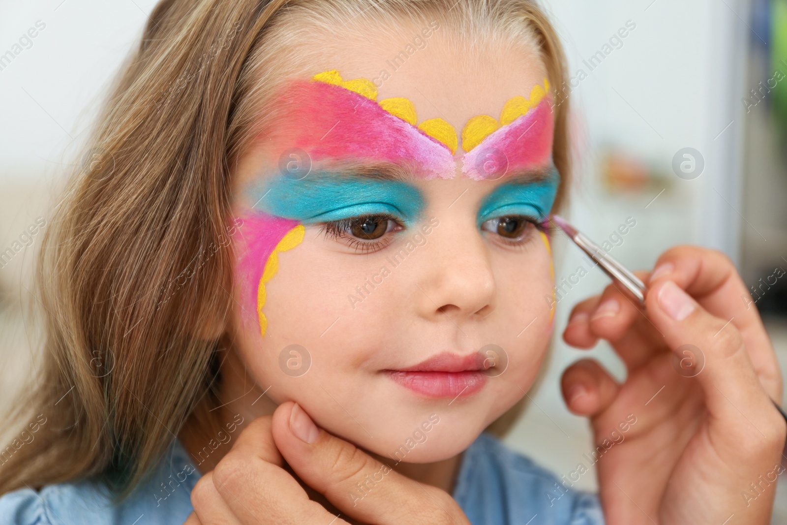 Photo of Artist painting face of little girl indoors