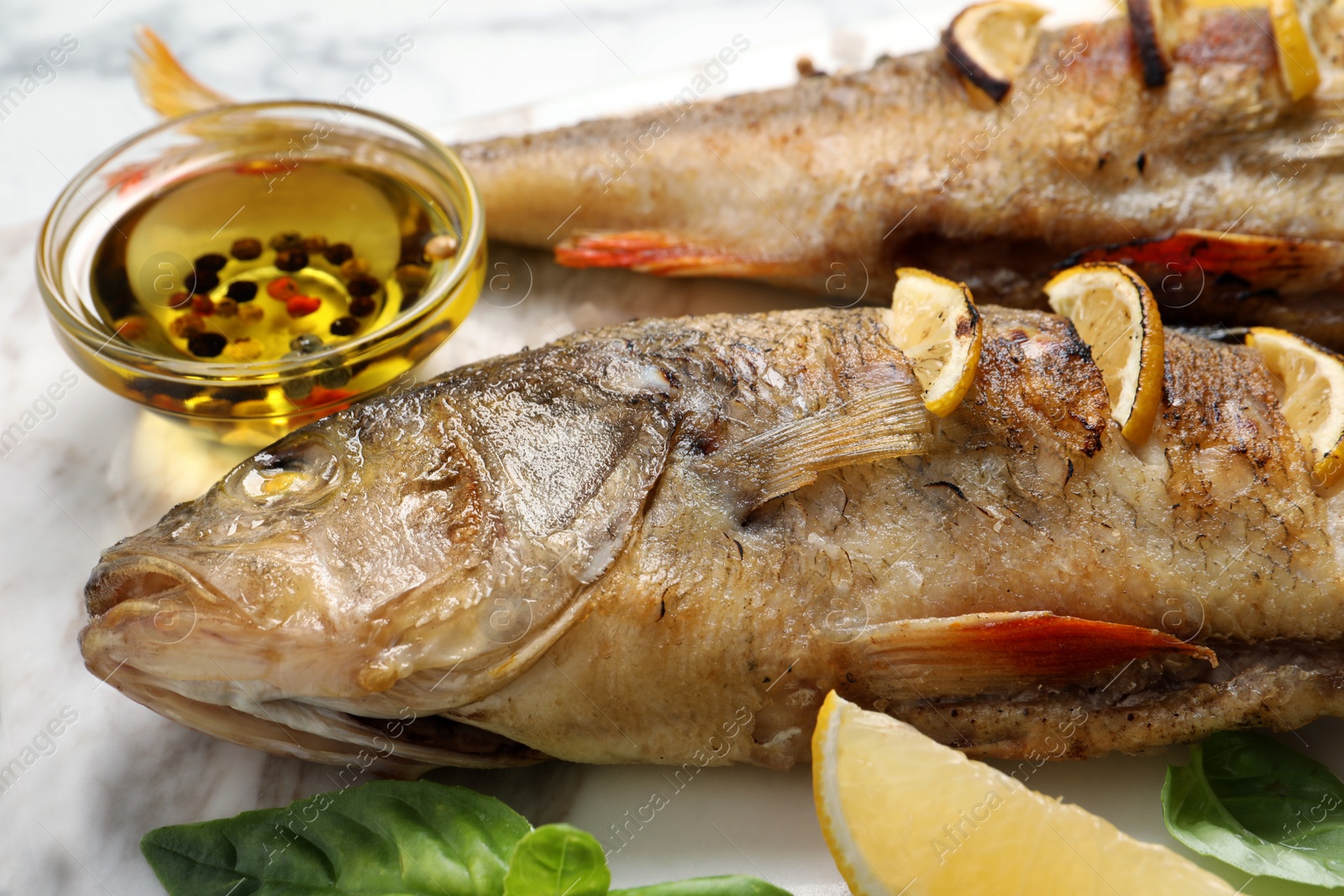 Photo of Tasty homemade roasted perches served on white board, closeup. River fish