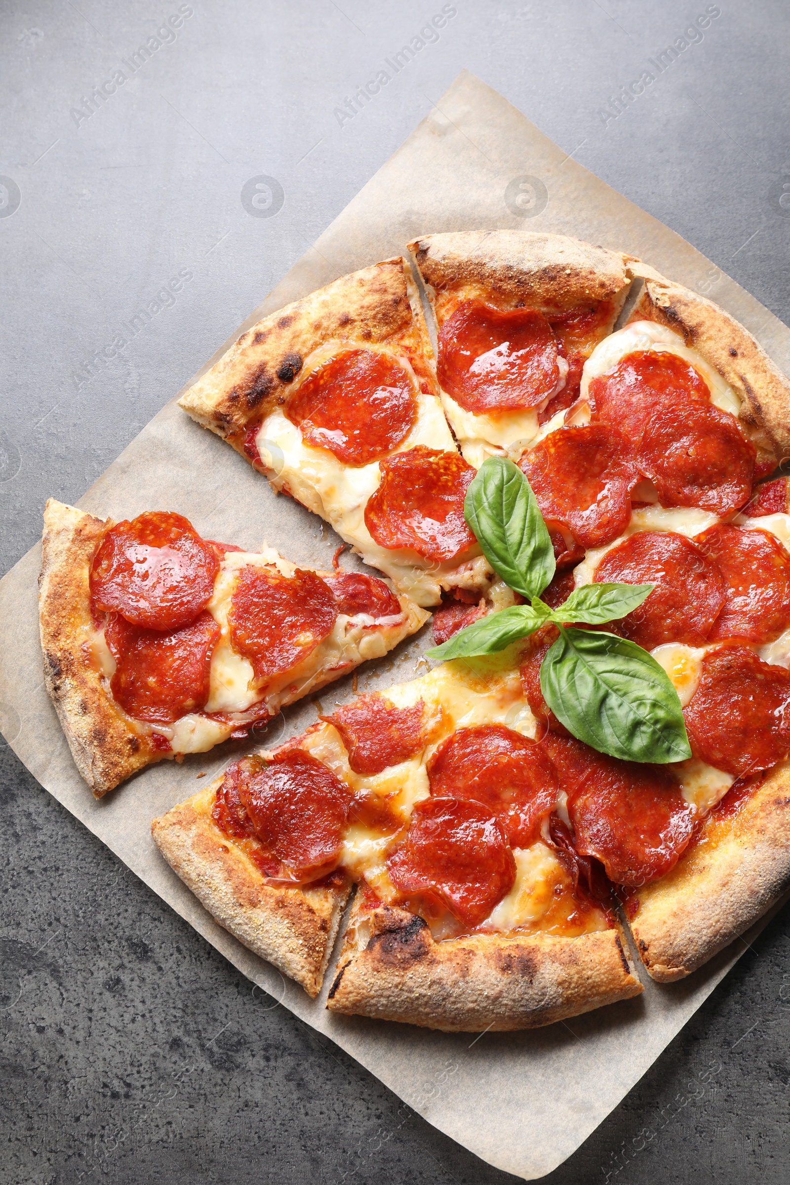 Photo of Tasty pepperoni pizza with basil on grey table, top view