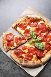 Tasty pepperoni pizza with basil on grey table, top view