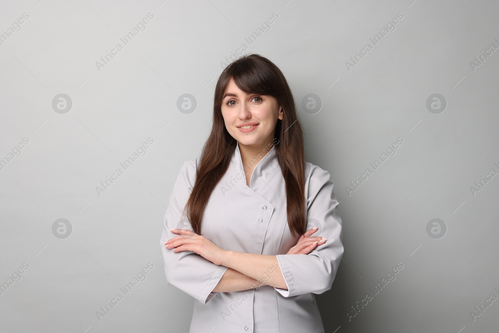 Photo of Cosmetologist in medical uniform on grey background