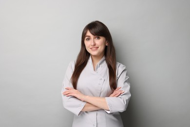 Cosmetologist in medical uniform on grey background