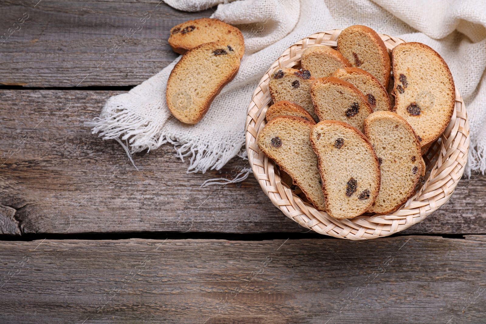 Photo of Sweet hard chuck crackers with raisins in wicker basket on wooden table, flat lay. Space for text