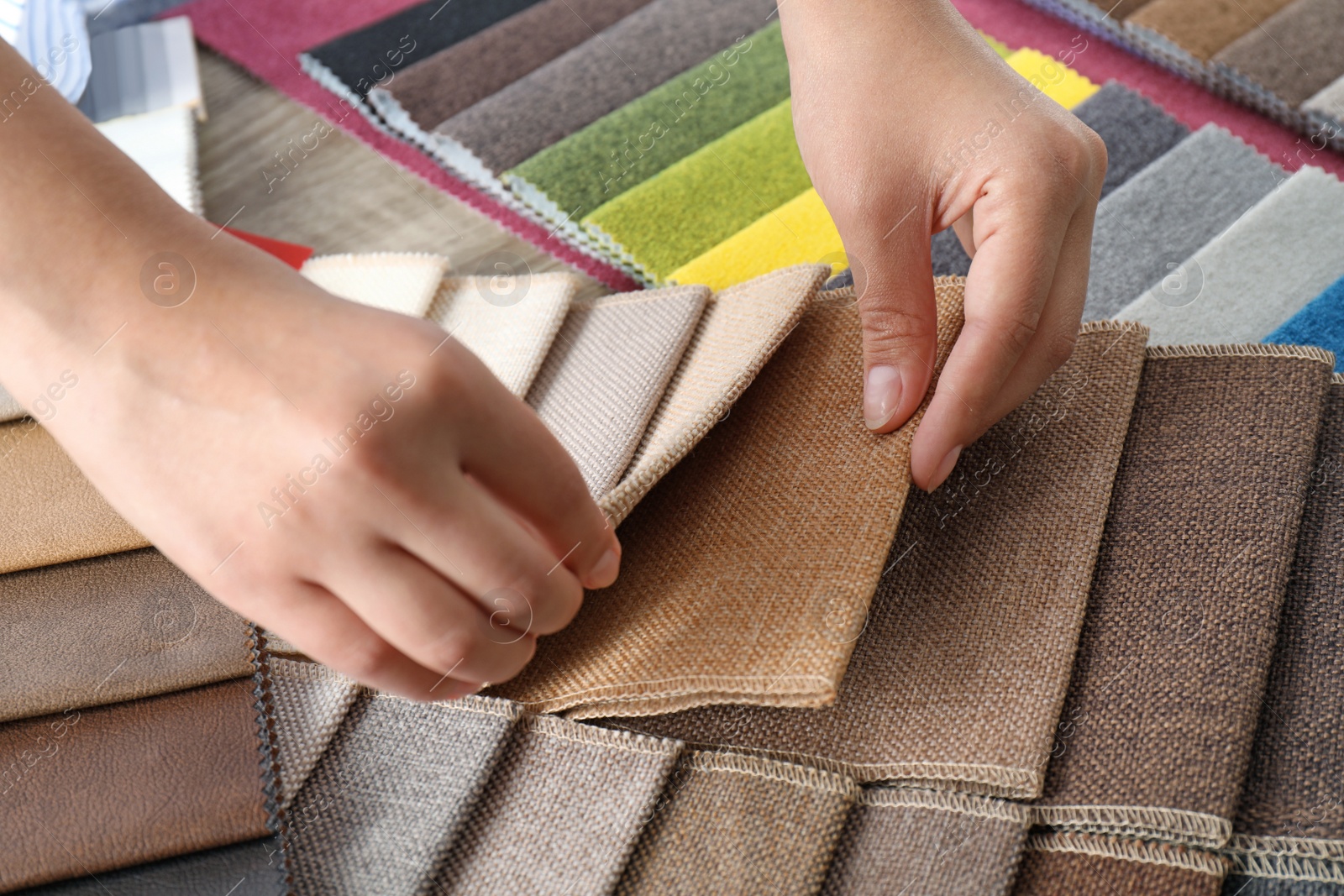 Photo of Young woman choosing among upholstery fabric samples, closeup. Interior design