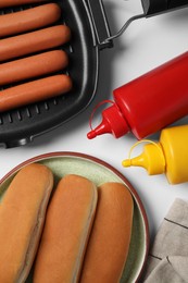 Different tasty ingredients for hot dog on white table, flat lay
