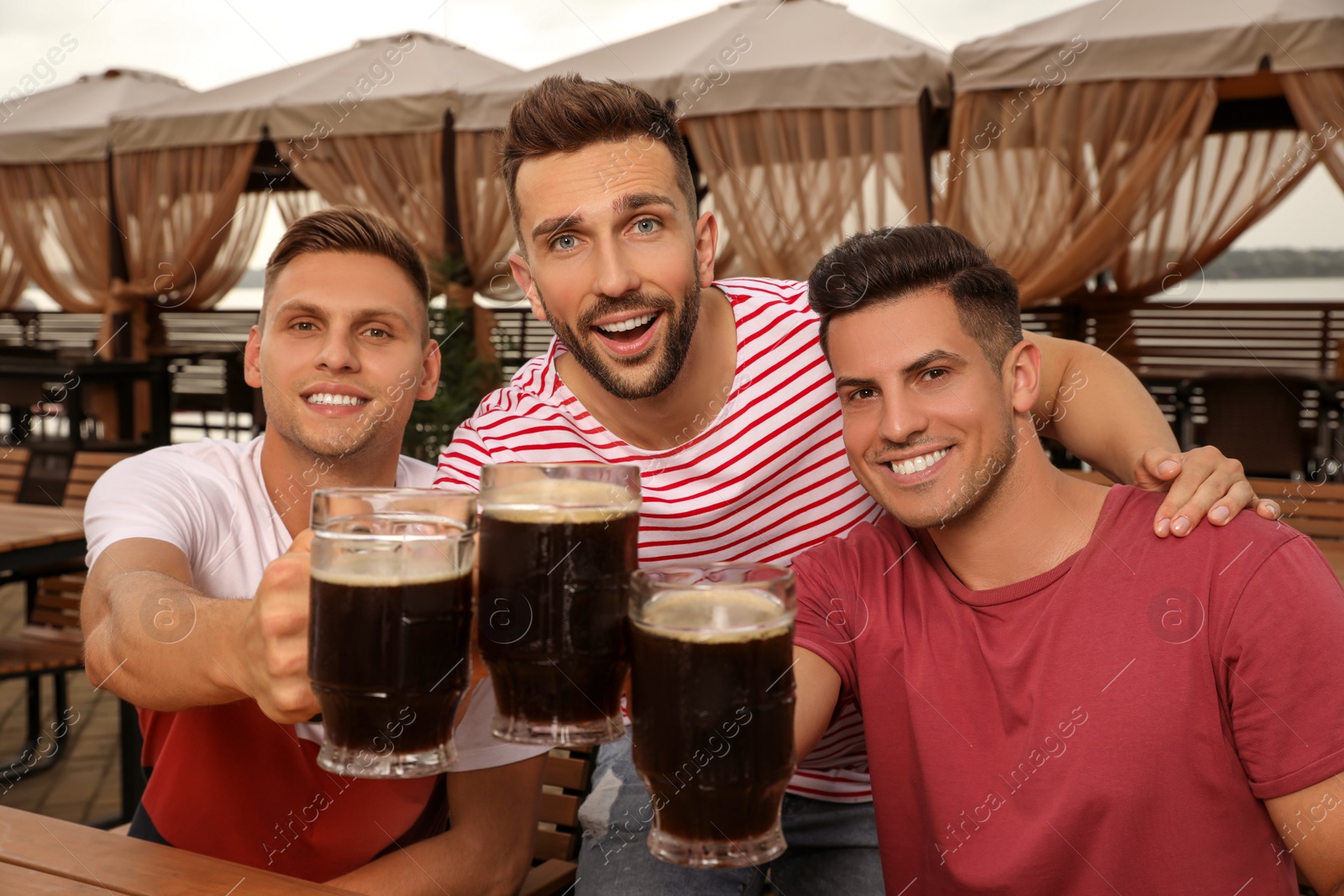 Photo of Friends clinking glasses of beer in outdoor cafe