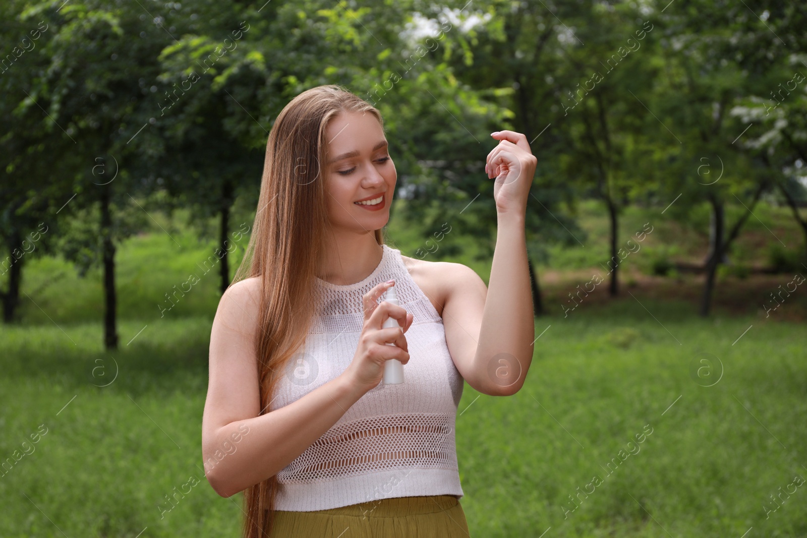 Photo of Woman applying insect repellent onto arm in park. Tick bites prevention