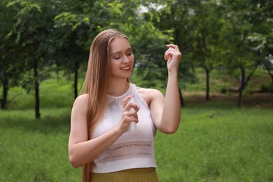 Woman applying insect repellent onto arm in park. Tick bites prevention