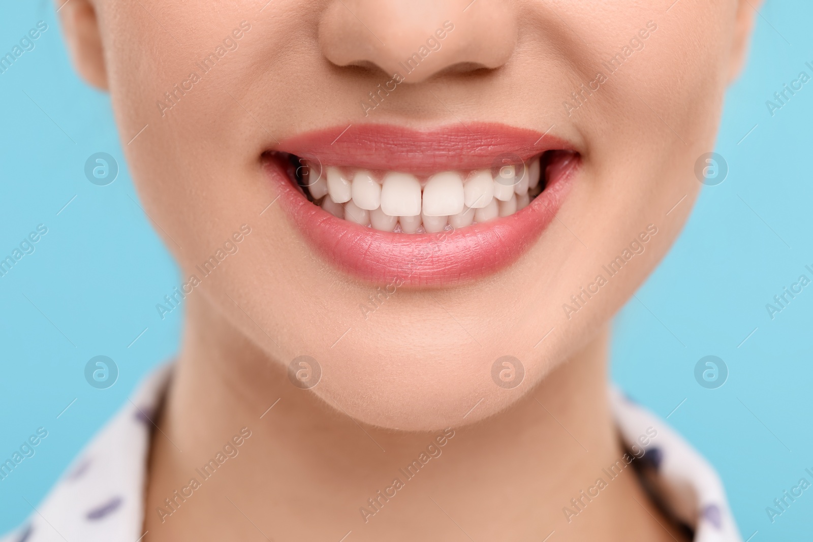 Photo of Woman with clean teeth smiling on light blue background, closeup