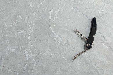 One corkscrew (sommelier knife) on grey marble table, top view. Space for text