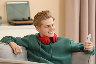 Teenage boy with headphones using smartphone at home