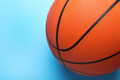 Orange ball on light blue background, top view with space for text. Basketball equipment