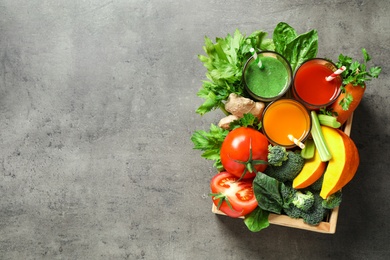 Photo of Delicious vegetable juices and fresh ingredients on grey table, top view. Space for text