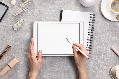 Photo of Woman with modern tablet at light grey table, top view. Space for text