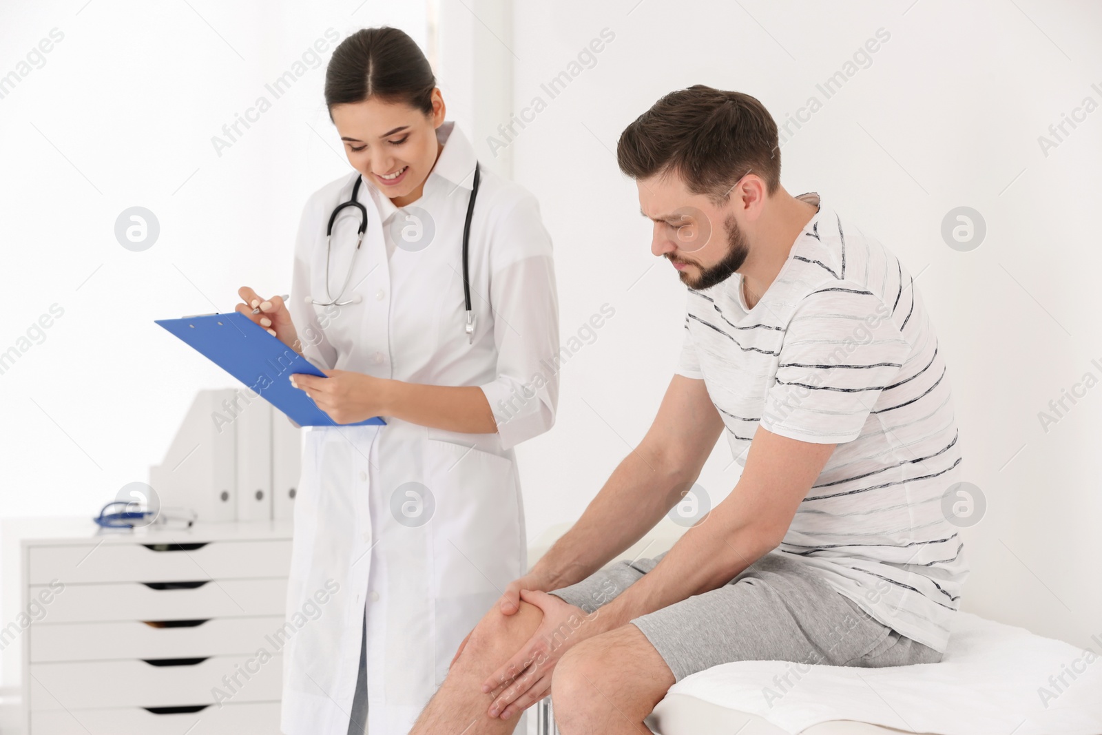 Photo of Doctor examining male patient with injured leg in clinic