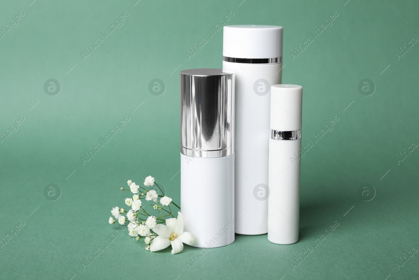 Photo of Set of luxury cosmetic products and flowers on blue-green background