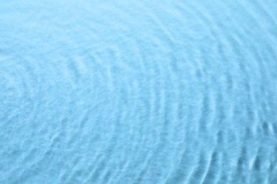 Image of Rippled surface of clear water on light blue background, closeup