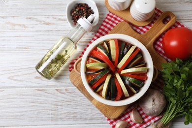 Cooking delicious ratatouille. Dish with different fresh cut vegetables on white wooden table, flat lay. Space for text