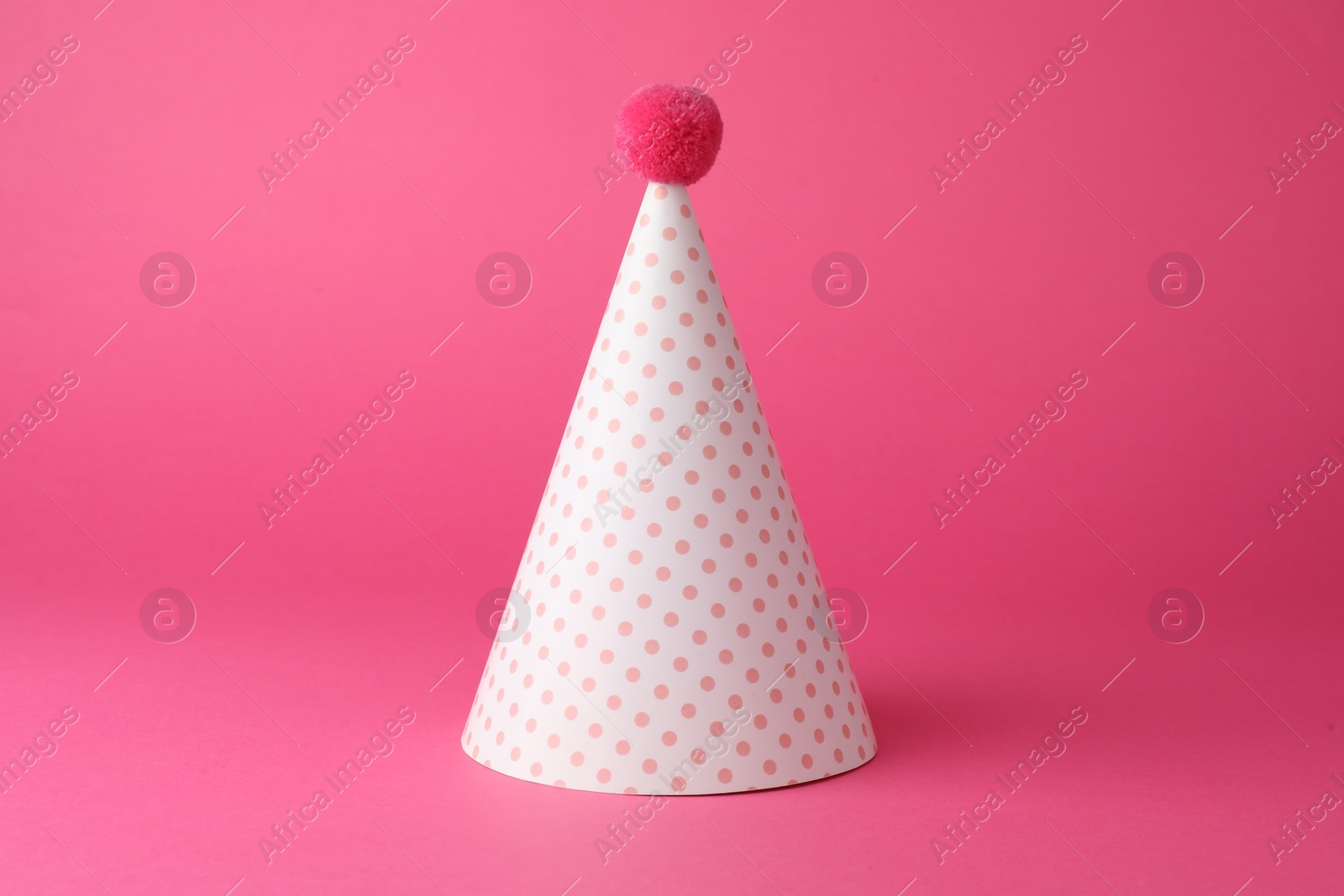 Photo of One beautiful party hat with pompom on pink background