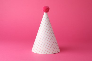 One beautiful party hat with pompom on pink background