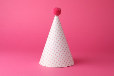 Photo of One beautiful party hat with pompom on pink background