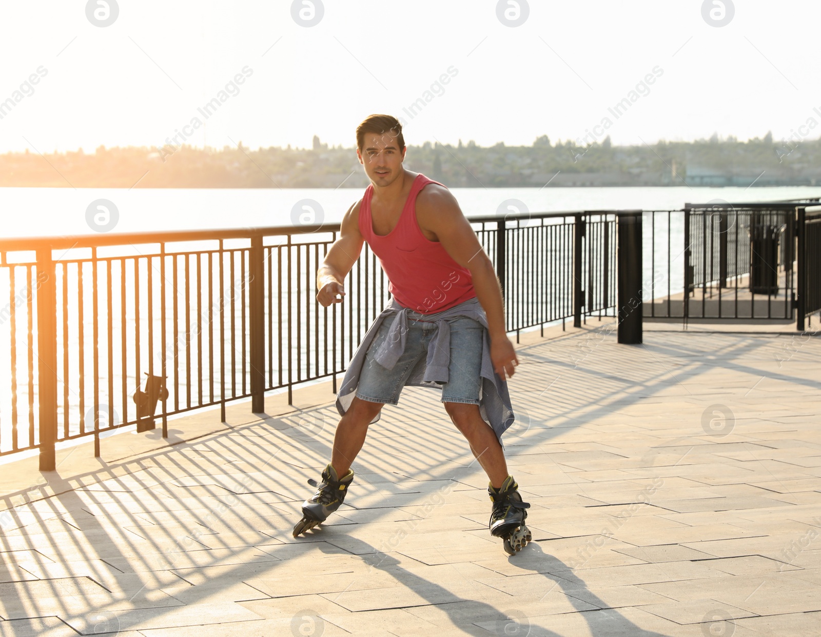 Photo of Handsome young man roller skating on pier near river